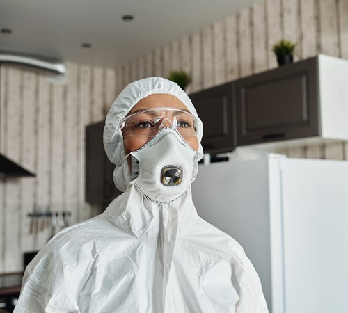 Woman in PPE including face mask, goggles, and overalls